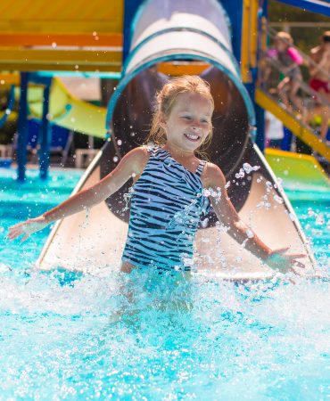 Kid on water slide at aquapark at summer holiday